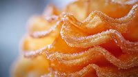 Extreme close-up macro shot of crispy wavy potato chips with salt crystals and textured ridges on blurred background, showing detailed snack food texture.