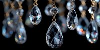Elegant crystal chandelier drops hanging on golden chains creating luxurious lighting decor with sparkling reflections against dark background for interior design.