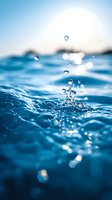 Crystal clear water drops splashing above blue ocean surface with sunlight creating bokeh effect and natural lens flare, macro photography showing liquid dynamics.