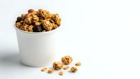 Homemade granola with nuts and dried fruits in white bowl on clean background. Healthy breakfast cereal mix for morning meal and snack recipes.