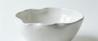 White ceramic bowl with organic wavy rim isolated on white background for kitchen design and culinary presentations.