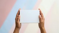 Hands holding blank white card against pastel striped background, mockup for branding, advertising, and promotional material display.