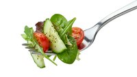 Fresh mixed salad with cucumber, cherry tomatoes and spinach leaves on fork isolated on white background for healthy eating and diet concepts.