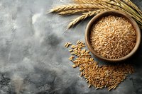 Raw wheat grains in wooden bowl with wheat ears on gray concrete background, agricultural harvest concept for healthy cooking.