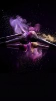 Makeup brushes with colorful powder explosion on black background for cosmetic and beauty industry advertising.