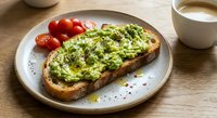 Healthy avocado toast with cherry tomatoes and seeds on rustic wooden table, nutritious breakfast meal with coffee cup for morning dining concept.