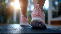Close up view of pink athletic sneaker on running track at sunset, female jogger stepping forward with modern mesh sport shoes during outdoor workout session.