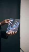 Businessman hands holding transparent tablet displaying holographic financial growth charts and data analytics in modern office environment.