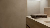 Minimalist bathroom interior with folded towel on beige stone countertop, neutral tones, modern design, suitable for home decor and interior design projects.