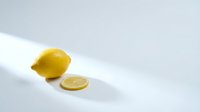Fresh yellow lemon with sliced round on clean white surface with soft natural lighting for culinary and healthy lifestyle concepts.
