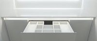 Modern minimalist kitchen drawer organizer with white compartments in sleek gray cabinet, perfect for utensil storage and home organization solutions.
