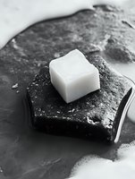 Solid shampoo bar on dark stone soap dish with foam, monochrome spa aesthetic for natural hair care and zero waste beauty concepts.