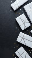 White gift boxes with silver ribbons arranged on dark slate background with gold and silver star confetti for holiday celebrations and special occasions.