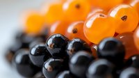 Fresh black and orange caviar pearls closeup macro shot showing gourmet delicacies texture and glossy spherical beads for luxury culinary presentations.