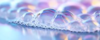 Frozen soap bubbles with rainbow iridescent reflections on winter snow surface create magical macro photography pattern in pink and blue colors.
