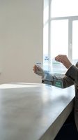 Businessperson in dark suit holding stacked confidential documents at white desk near bright window, symbolizing data security and corporate information management.
