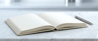 Open blank notebook with silver pen on white surface ready for writing notes planning or journaling in minimalist workspace setting.