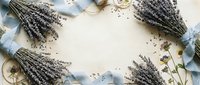 Dried lavender bunches arranged in frame border with scattered flowers and twine on rustic wooden background for aromatherapy and natural wellness concepts.