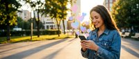Young woman using smartphone outdoors in urban park setting during golden hour sunset with warm natural lighting for lifestyle and technology concepts.