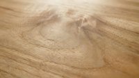Close-up of natural wood grain texture with warm tan tones and swirling patterns, suitable for backgrounds, flooring design, and interior decoration projects.