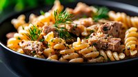 Savory pasta with seasoned ground meat and fresh dill herbs in black skillet. Homemade comfort food recipe for family dinner and cooking content.