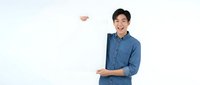 Young Asian man wearing blue denim shirt holding blank white sign on white background for advertising and promotional messaging.