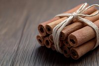 Bundle of cinnamon sticks tied with natural twine rope on rustic wooden surface for cooking, baking and spice applications.