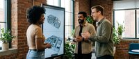 Young diverse business team collaborating in modern brick office space during creative brainstorming session with charts and plants.