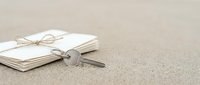 Open notebook with twine bow and silver key on sandy beige surface, symbolizing secrets, access, knowledge, and discovery for editorial and conceptual design projects.