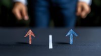 Conceptual choice and decision making metaphor with red and blue chalk arrows pointing upward on dark surface, divided by white line.
