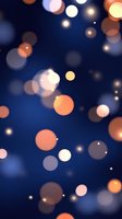 Glowing orange and white bokeh lights floating on deep blue background create dreamy atmospheric effect for festive designs and holiday backgrounds.