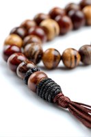 Close-up of wooden prayer beads with brown tassel on white background, featuring polished tiger eye and dark wood spheres for meditation.
