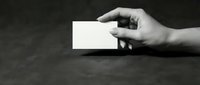 Hand holding blank white business card on dark surface for corporate branding and professional networking mockup template design.