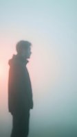 Silhouetted male figure standing in heavy fog at dawn, wearing casual jacket, conveying solitude, contemplation, and atmospheric mystery for editorial and conceptual projects.