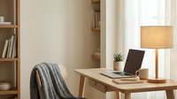 Modern home office workspace with wooden desk, laptop, floor lamp and bookshelf in warm natural lighting for remote work and productivity.