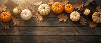 Autumn pumpkins and fall leaves arranged on rustic wooden background with warm candlelight creating cozy seasonal atmosphere for harvest decorations.