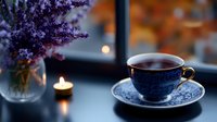 Serene evening tea setting with blue porcelain cup, lavender bouquet in glass vase, and glowing candle creating cozy atmosphere near window. Soft bokeh background.