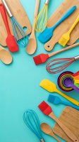 Colorful kitchen utensils and baking tools arranged on turquoise background. Wooden spoons, silicone spatulas, whisks and measuring cups for cooking preparation.