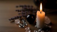 Burning candle with crystals and lavender creating peaceful meditation atmosphere for spiritual wellness and relaxation practices.