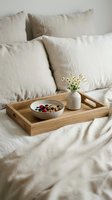 Wooden breakfast tray with healthy granola bowl and flowers on cozy beige linen bedding for morning routine and self-care lifestyle.