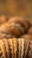 Natural brown wool yarn threads in close-up macro detail with soft blurred background for textile and craft projects.