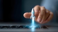 Small rocket launching from keyboard with glowing blue thrust effect and hand reaching towards it, symbolizing business startup and technological innovation concept.