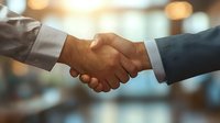 Close-up of diverse business professionals handshake against blurred office background, symbolizing partnership, trust, and successful deal completion.