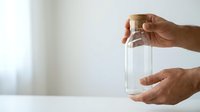 Male hands holding empty glass jar against white background, suitable for business concepts, storage solutions, and product packaging presentations.