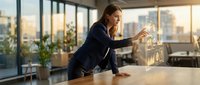 Professional businesswoman analyzing holographic financial data charts and graphs in modern office with city skyline view during golden hour sunset.