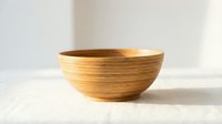 Handcrafted wooden bowl with natural grain texture on a linen surface, soft light background, rustic minimalist kitchen decor concept.