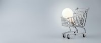 Shopping cart filled with glowing light bulb on white background, representing energy savings, eco-friendly shopping, and sustainable consumer choices for retail and business concepts.