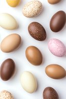 Colorful farm fresh eggs in various natural shades of brown, pink, cream and speckled patterns arranged on white background, isolated overhead view.