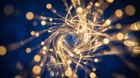Golden light trails swirling in spiral motion with bokeh effects on dark blue background for creative design projects and digital art concepts.