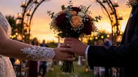 Bride and groom holding wedding bouquet during sunset ceremony with decorative arch and warm lighting creating romantic atmosphere for marriage celebration.